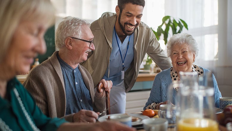 Group of cheerful seniors enjoying breakfast in nursing home care center