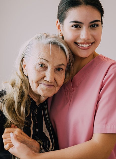 Happy-caregiver-and-senior-patient-smiling-and-looking-at-camera