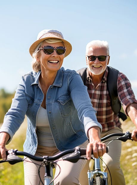 Happy older couple explores nature by bike on sunny day