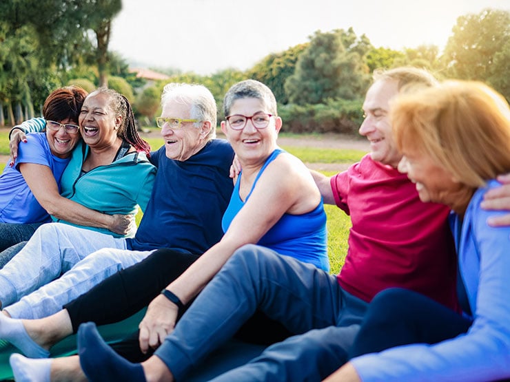 Happy senior people after yoga sport class having fun sitting outdoors in park city