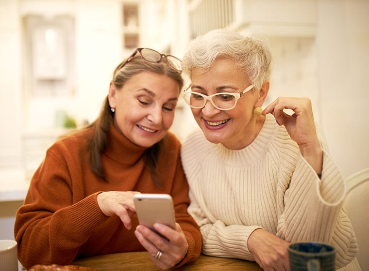 Two senior ladies chatting and looking at a mobile phone together