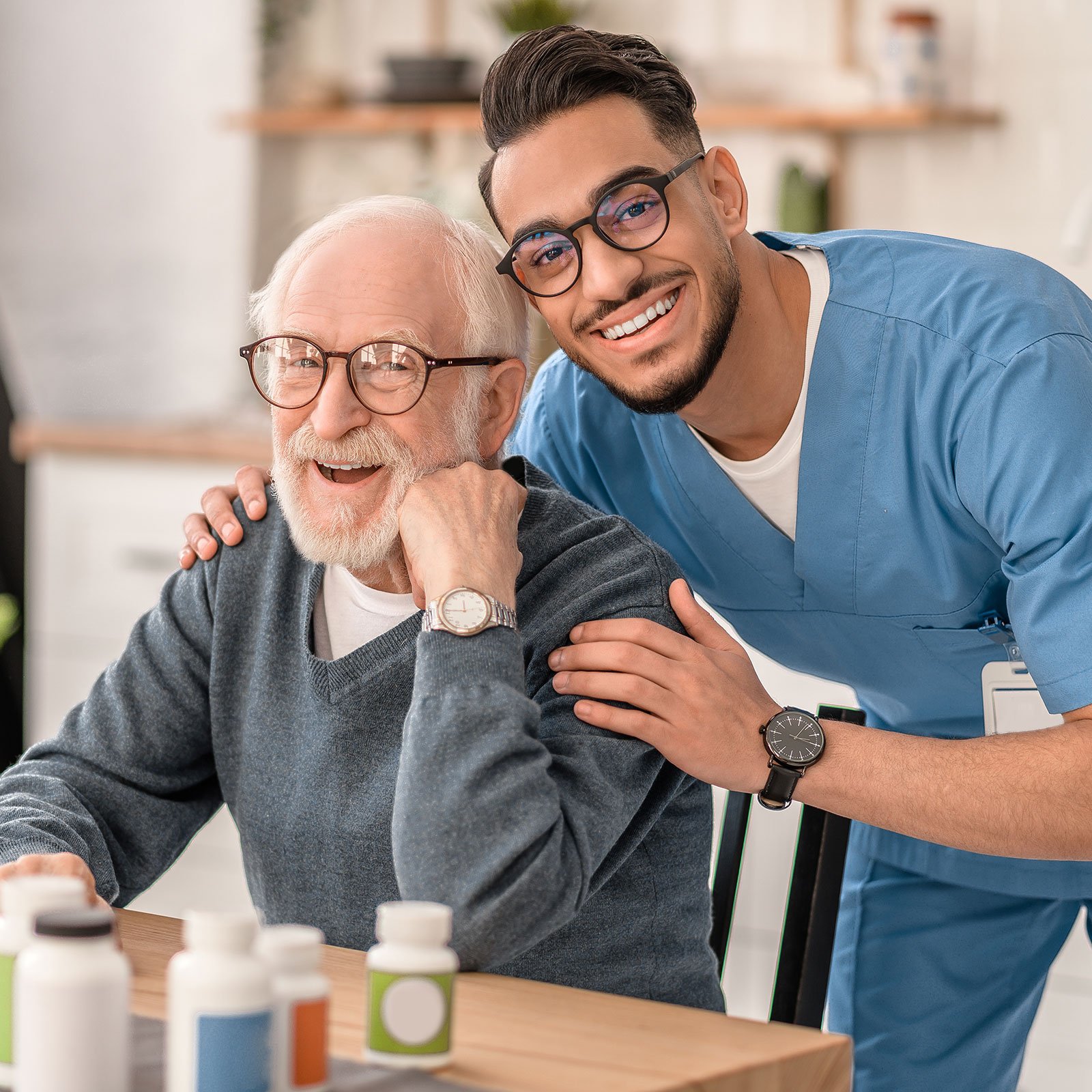 A male nurse hugging a senior man as they both smile. 