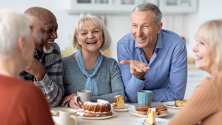 Multiracial group of happy senior people drinking tea with cake
