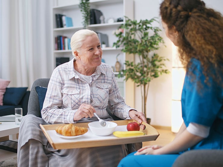 Nurse bringing meal to senior woman in a retirement home