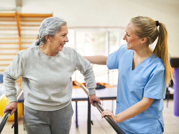 Physiotherapist-assisting-elderly-woman-in-movement-therapy-at-rehab-center