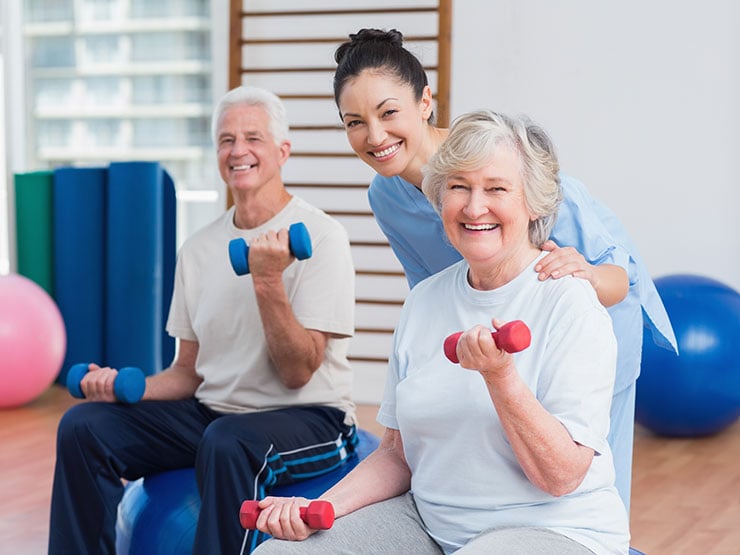 Portrait of happy fitness instructor with senior couple