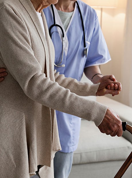 Senior woman with a cane getting assistance in elderly care facility