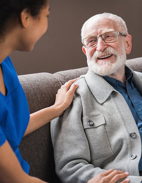 Friendly caregiver talking chatting to happy senior man