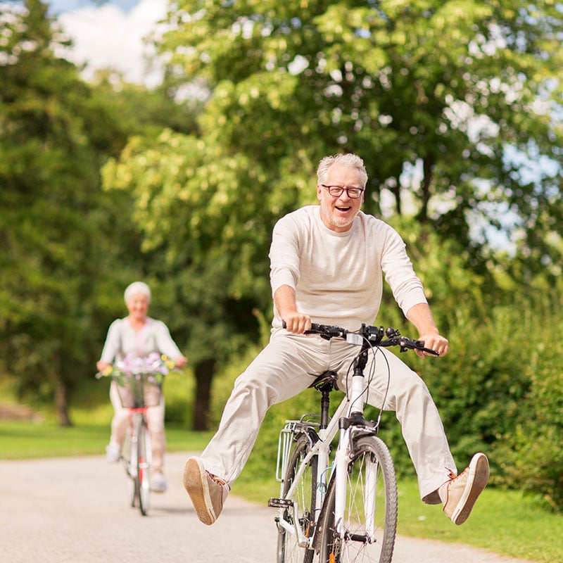 happy senior couple riding bicycles at summer park