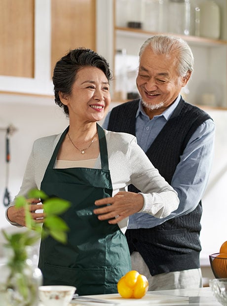 senior asian man helping wife putting on apron