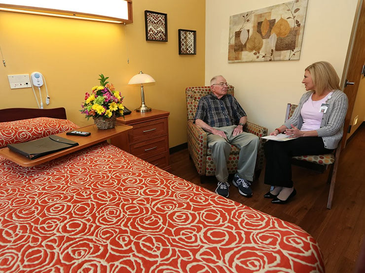 senior man and caregiver talking in a bedroom
