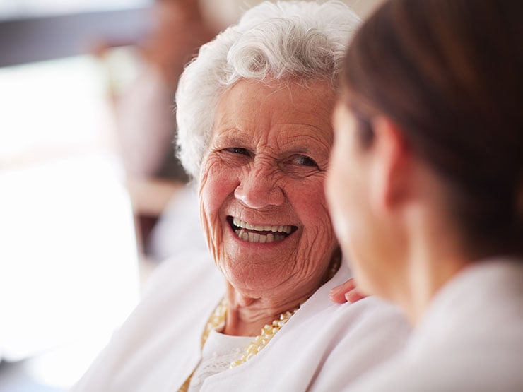 senior woman and caregiver smiling