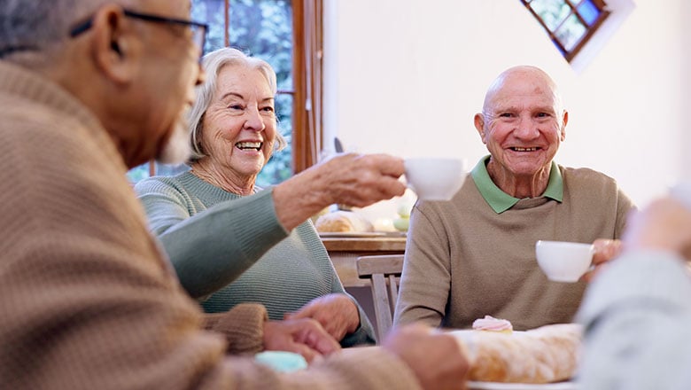 Cheers with happy senior men and women together in an apartment