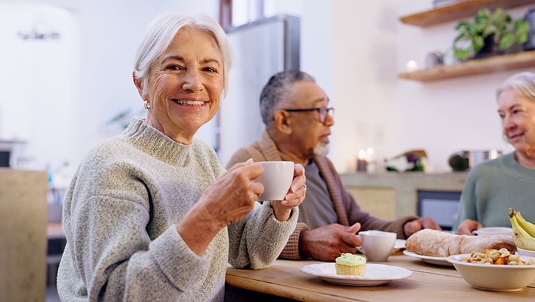 Tea party and a group of senior people in the living room of a community home for a social