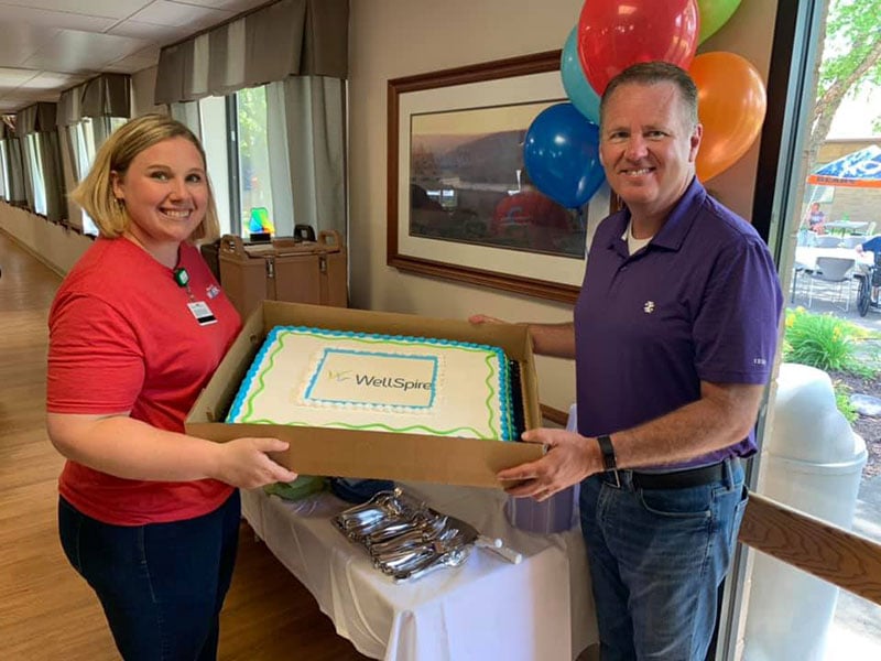 man and woman holding a cake looking into the camera