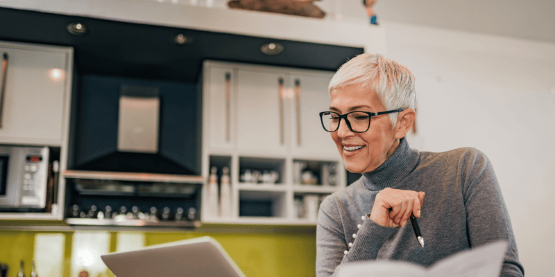 A happy older woman reviewing independent living costs on her laptop.