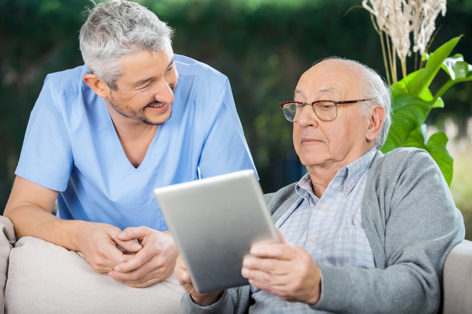 A senior man showing his nurse something on his tablet
