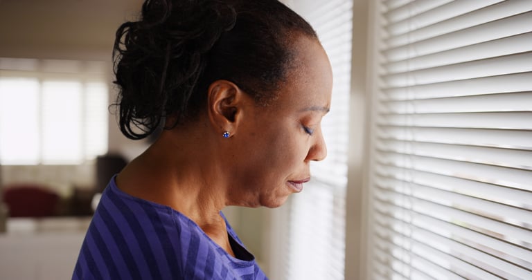 Woman staring outside window with a grim expression