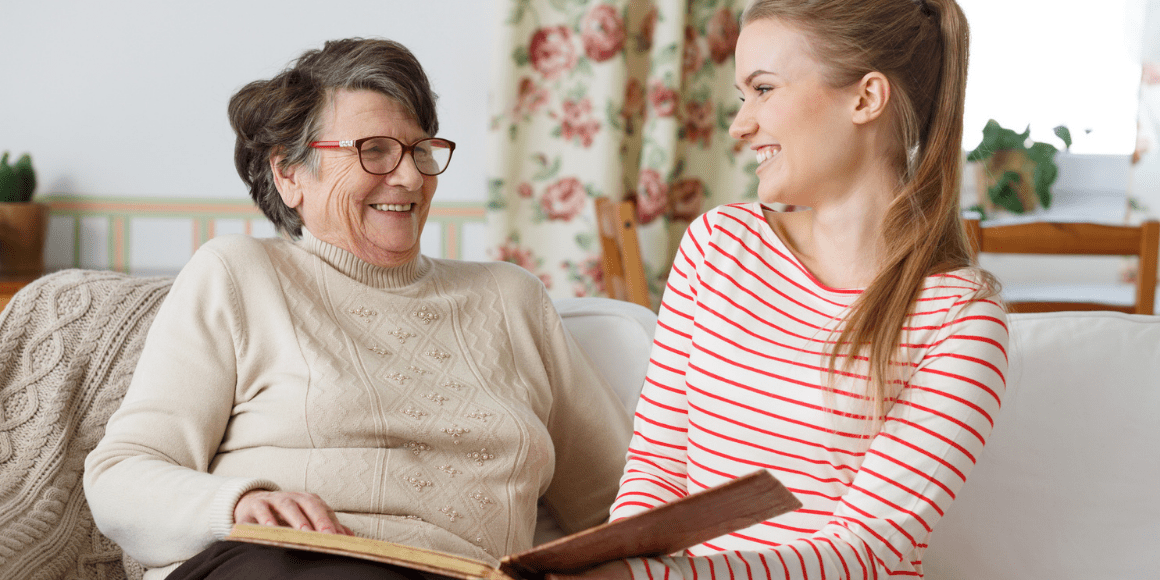 mother and daughter sitting on couch while reading a book